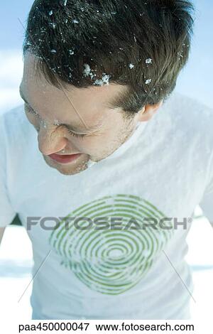 Stock Photo - Young man in snow, eyes closed, dressed in tee-shirt. Fotosearch