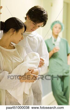 Couple standing, looking at newborn baby together, doctor in background View Large Photo Image Stock Photo - Couple standing, looking at newborn baby together, doctor in background. Fotosearch