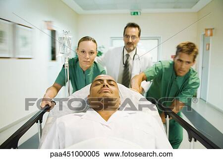 Stock Photography - Emergency room staff pushing man on stretcher. Fotosearch