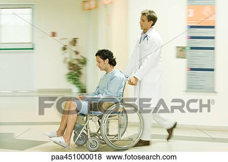 Stock Photo - Male doctor pushing man in wheelchair, full length. Fotosearch