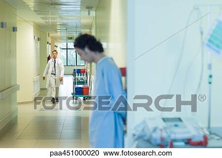 Male doctor walking in hospital corridor, patient in foreground View Large Photo Image Stock Image - Male doctor walking in hospital corridor, patient in foreground. Fotosearch