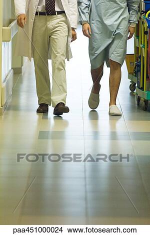 Male doctor walking with patient in hospital corridor, cropped view of legs View Large Photo Image Picture - Male doctor walking with patient in hospital corridor, cropped view of legs. Fotosearch