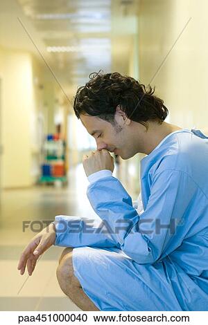 Male patient crouching in hospital corridor, holding head, looking down View Large Photo Image Stock Image - Male patient crouching in hospital corridor, holding head, looking down. Fotosearch