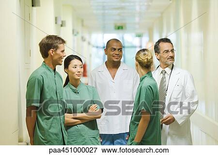 Medical staff standing in hallway, chatting, looking away View Large Photo Image Stock Photo - Medical staff standing in hallway, chatting, looking away. Fotosearch