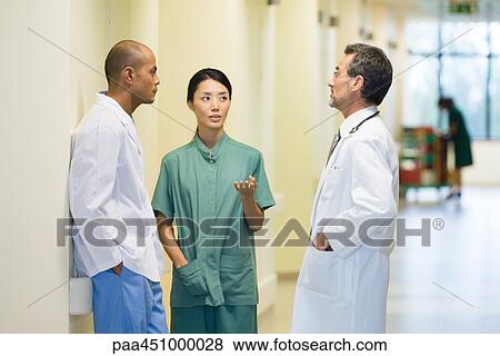 Medical staff standing in hallway, discussing, looking at each other View Large Photo Image Stock Photo - Medical staff standing in hallway, discussing, looking at each other. Fotosearch