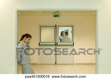 Woman using cell phone in hospital waiting room, doctor and patient in background View Large Photo Image Stock Photograph - Woman using cell phone in hospital waiting room, doctor and patient in background. Fotosearch