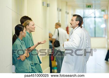 Young hospital staff chatting with mature male doctor, side view View Large Photo Image Stock Photography - Young hospital staff chatting with mature male doctor, side view. Fotosearch