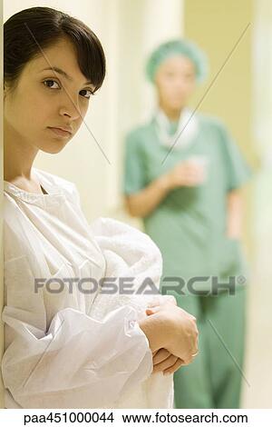 Young woman holding newborn baby, looking at camera, medical worker in background View Large Photo Image Picture - Young woman holding newborn baby, looking at camera, medical worker in background. Fotosearch
