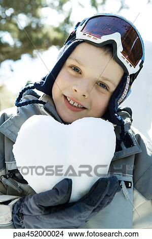 Boy in ski gear holding heart made of snow, portrait View Large Photo Image Picture - Boy in ski gear holding heart made of snow, portrait. Fotosearch