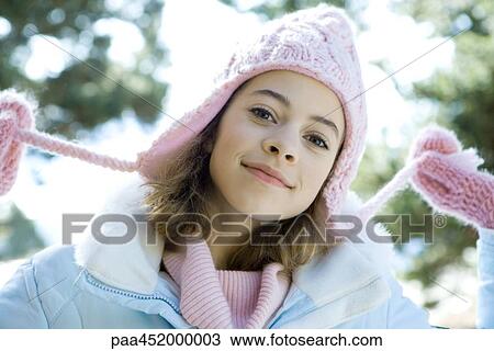 Stock Image - Preteen girl holding strings of knit hat, portrait. Fotosearch