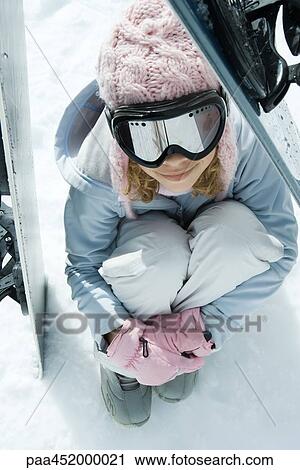 Preteen girl sitting on snow underneath propped up snowboards, high angle view View Large Photo Image Stock Image - Preteen girl sitting on snow underneath propped up snowboards, high angle view. Fotosearch