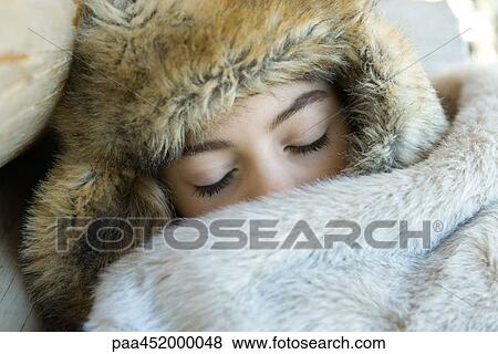 Stock Photo - Preteen girl, wearing fur hat, sleeping under fur blanket, close-up. Fotosearch