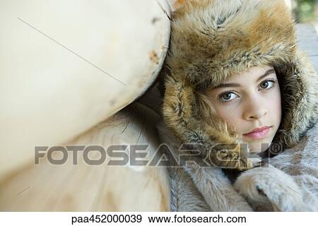 Stock Photo - Preteen girl, wearing fur hat, wrapped in fur blanket, close-up. Fotosearch