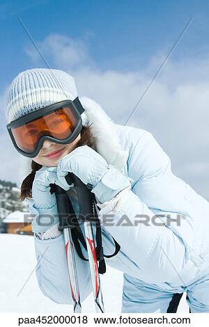 Stock Photo - Teen girl leaning on ski poles, smiling at camera. Fotosearch