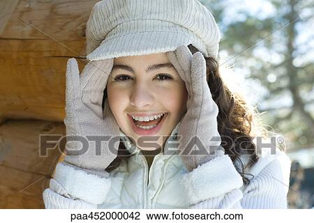 Teenage girl holding hands on side of face, smiling at camera View Large Photo Image Stock Image - Teenage girl holding hands on side of face, smiling at camera. Fotosearch