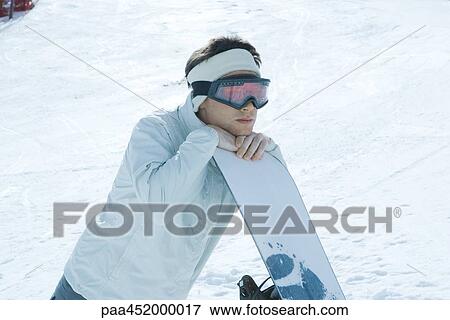 Young man leaning on snowboard View Large Photo Image Stock Photo - Young man leaning on snowboard. Fotosearch