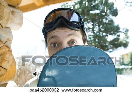 Young man looking over edge of snowboard View Large Photo Image Stock Image - Young man looking over edge of snowboard. Fotosearch