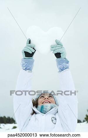 Young woman holding up heart made of snow View Large Photo Image Stock Image - Young woman holding up heart made of snow. Fotosearch