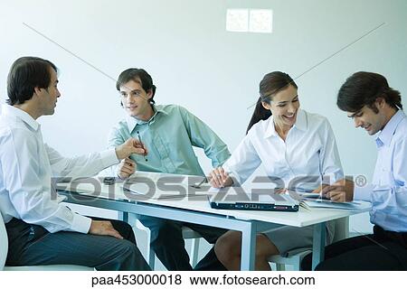 Business associates seated at table, chatting, three quarter length View Large Photo Image Stock Photo - Business associates seated at table, chatting, three quarter length. Fotosearch
