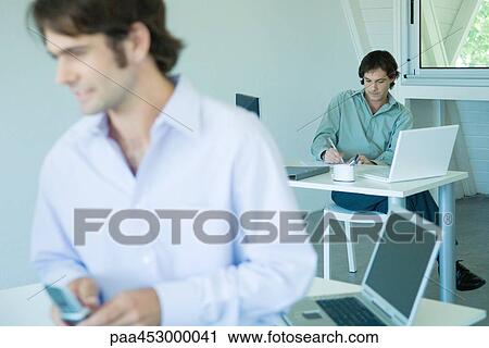 Businessman in office, writing, full length, associate in foreground View Large Photo Image Stock Image - Businessman in office, writing, full length, associate in foreground. Fotosearch