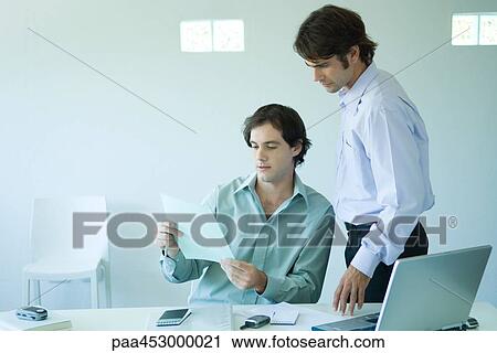 Two businessmen in office, looking at document View Large Photo Image Stock Image - Two businessmen in office, looking at document. Fotosearch