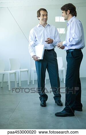 Two businessmen standing, looking at each other, full length View Large Photo Image Stock Image - Two businessmen standing, looking at each other, full length. Fotosearch