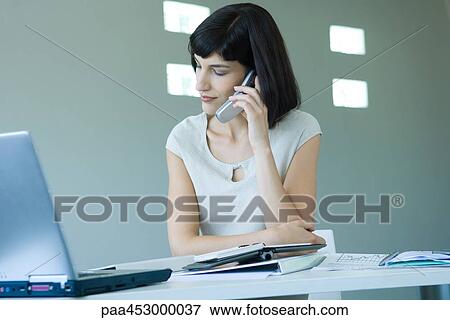 Young businesswoman in office, using cell phone, looking away View Large Photo Image Stock Photo - Young businesswoman in office, using cell phone, looking away. Fotosearch