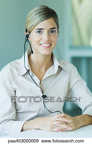Young businesswoman wearing headset, smiling at camera, waist up View Large Photo Image Stock Photo - Young businesswoman wearing headset, smiling at camera, waist up. Fotosearch