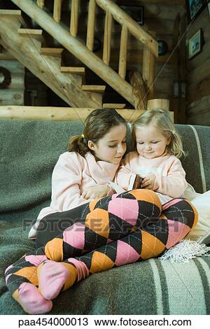 Girl and toddler sitting on couch, reading book, full length View Large Photo Image Stock Image - Girl and toddler sitting on couch, reading book, full length. Fotosearch