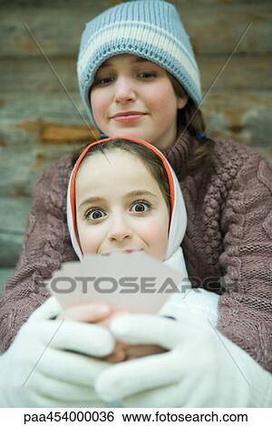 Girl holding cards, smiling at camera, friend looking at her cards, both dressed in winter clothing View Large Photo Image Stock Photograph - Girl holding cards, smiling at camera, friend looking at her cards, both dressed in winter clothing. Fotosearch