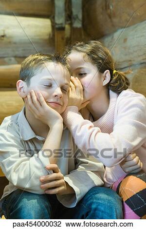 Girl whispering in boy's ear, boy closing eyes, smiling View Large Photo Image Stock Image - Girl whispering in boy's ear, boy closing eyes, smiling. Fotosearch