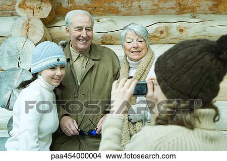 Teenage girl photographing grandparents and sister with digital camera, waist up View Large Photo Image Picture - Teenage girl photographing grandparents and sister with digital camera, waist up. Fotosearch