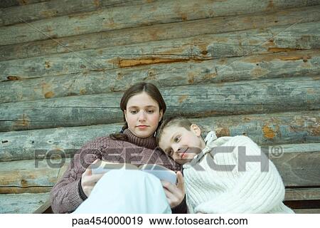 Teenage girl reading book, little brother resting head on her shoulder View Large Photo Image Stock Photo - Teenage girl reading book, little brother resting head on her shoulder. Fotosearch