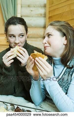 Two teenage girls eating crepes, looking at each other View Large Photo Image Stock Photo - Two teenage girls eating crepes, looking at each other. Fotosearch