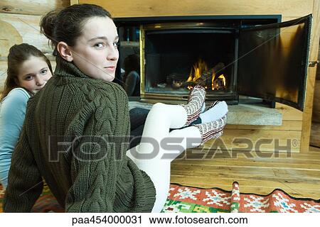 Two teenage girls sitting by fireplace, smiling at camera View Large Photo Image Stock Image - Two teenage girls sitting by fireplace, smiling at camera. Fotosearch