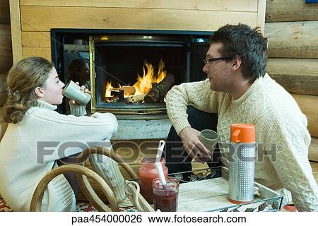 Young man and teenage girl sitting by fireplace, drinking hot beverages, looking at each other View Large Photo Image Stock Photograph - Young man and teenage girl sitting by fireplace, drinking hot beverages, looking at each other. Fotosearch
