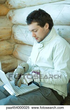 Young man using laptop computer, dressed in winter clothing, typing with gloves View Large Photo Image Stock Photography - Young man using laptop computer, dressed in winter clothing, typing with gloves. Fotosearch