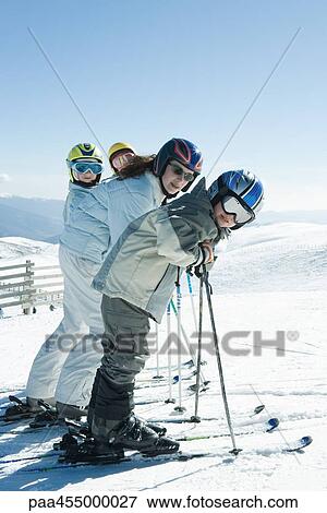 Four young skiers standing in a row, smiling at camera, group portrait View Large Photo Image Stock Photo - Four young skiers standing in a row, smiling at camera, group portrait. Fotosearch