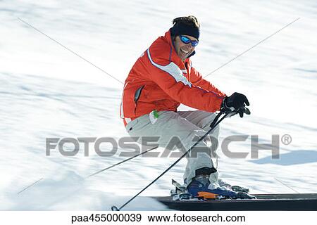 Stock Photo - Mature male skier on ski slope, smiling toward camera, blurred motion. Fotosearch