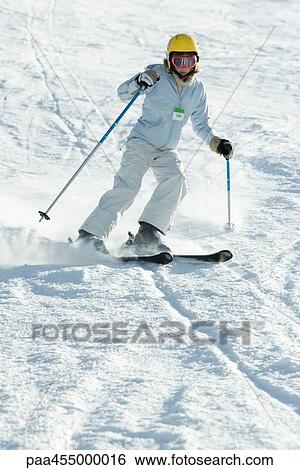 Stock Photograph - Teenage girl skiing down ski slope, full length. Fotosearch