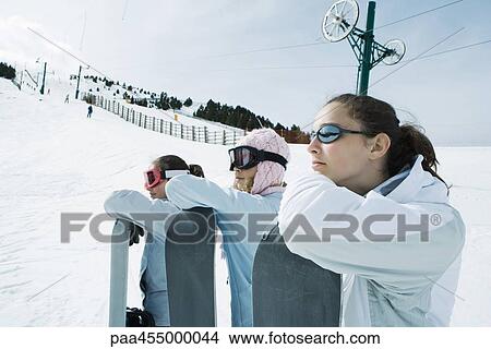 Three teenage girls lined up, leaning on snowboards, heads resting on arms View Large Photo Image Picture - Three teenage girls lined up, leaning on snowboards, heads resting on arms. Fotosearch