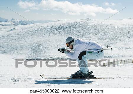 Young female skier crouching, side view, full length portrait View Large Photo Image Stock Image - Young female skier crouching, side view, full length portrait. Fotosearch
