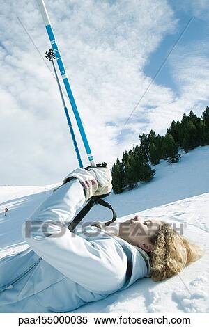 Young female skier lying on ground, holding up ski sticks, eyes closed View Large Photo Image Stock Photography - Young female skier lying on ground, holding up ski sticks, eyes closed. Fotosearch