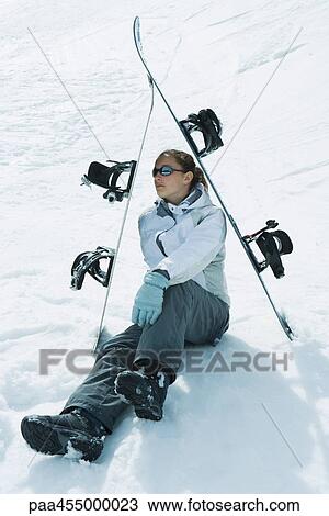Young female skier sitting on the ground under skis, looking away View Large Photo Image Stock Image - Young female skier sitting on the ground under skis, looking away. Fotosearch