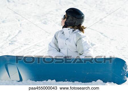 Young female snowboarder sitting on ground, looking away View Large Photo Image Stock Image - Young female snowboarder sitting on ground, looking away. Fotosearch