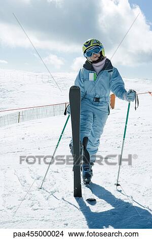 Picture - Young skier standing with one leg up, smiling at camera, full length portrait. Fotosearch