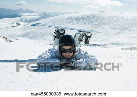 Young snowboarder lying on the ground, head resting on arms, smiling at camera View Large Photo Image Stock Photograph - Young snowboarder lying on the ground, head resting on arms, smiling at camera. Fotosearch