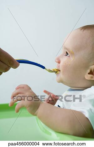 Baby being fed with spoon, side view View Large Photo Image Picture - Baby being fed with spoon, side view. Fotosearch