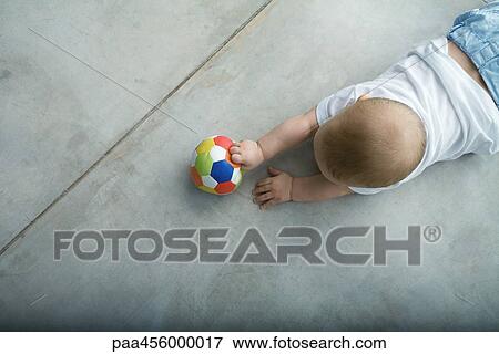 Baby crawling on floor, holding ball, view from directly above View Large Photo Image Stock Photo - Baby crawling on floor, holding ball, view from directly above. Fotosearch