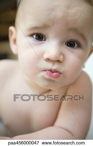 Stock Photo - Baby frowning at camera, portrait. Fotosearch